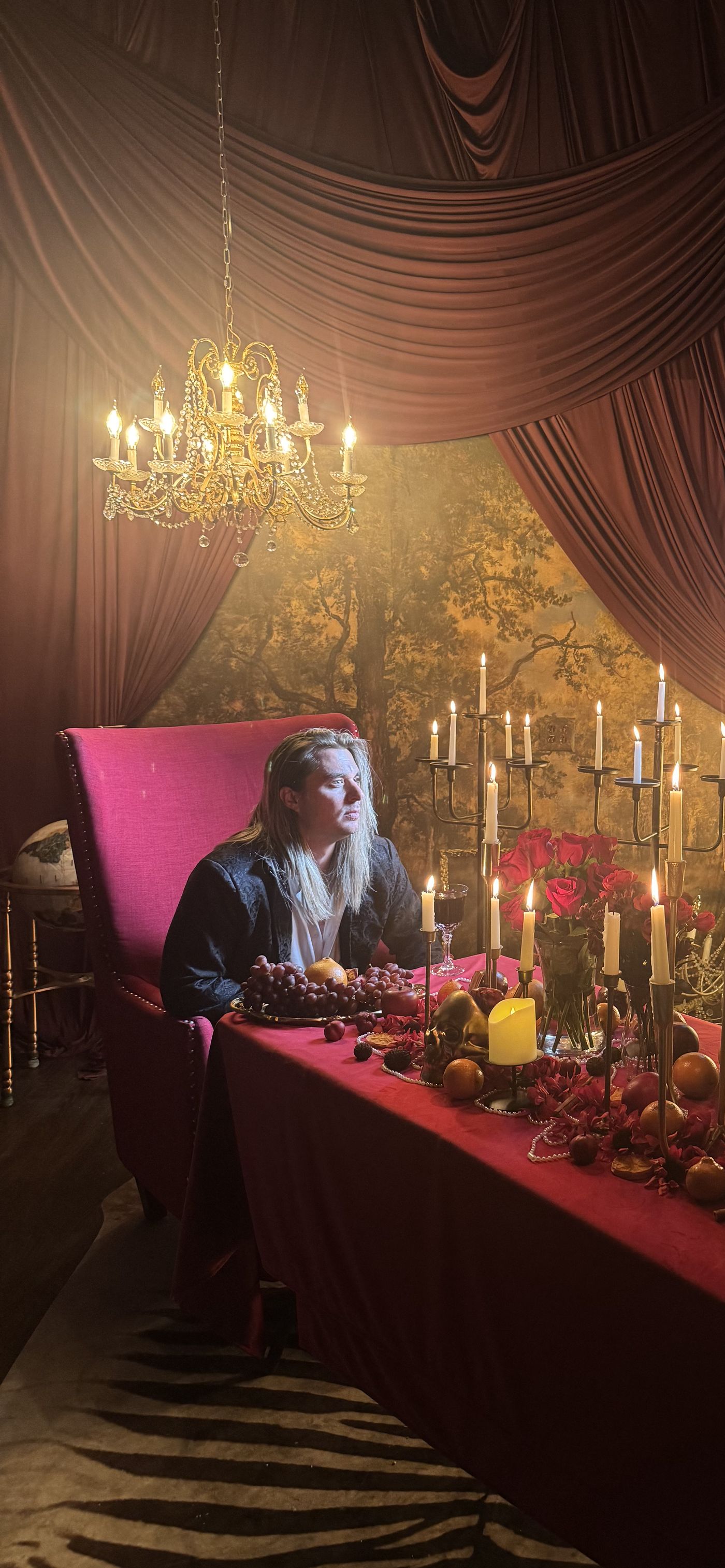 Jay Putty at a long candlelit table in a red room